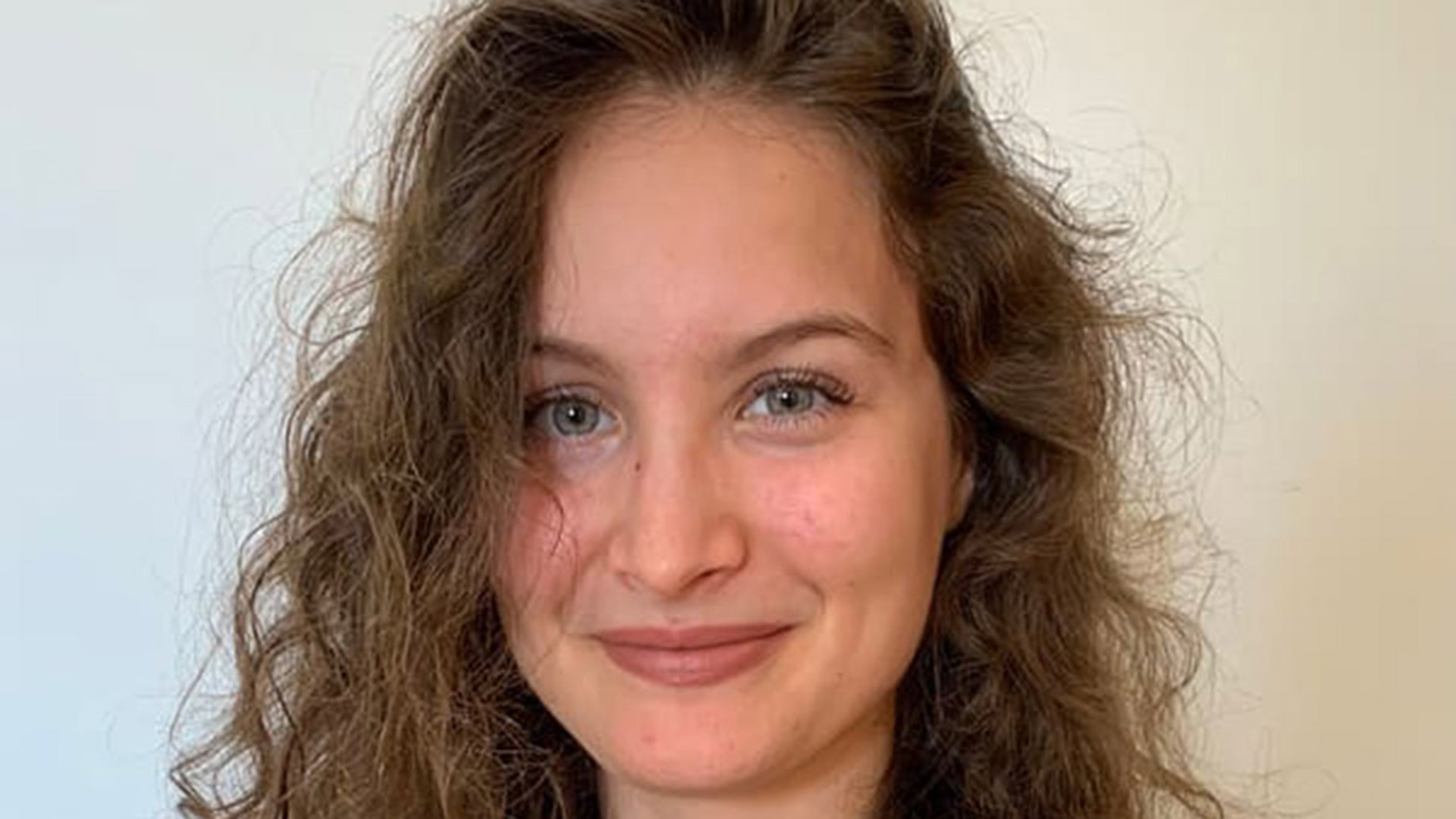 A woman with curly hair is smiling for the camera.